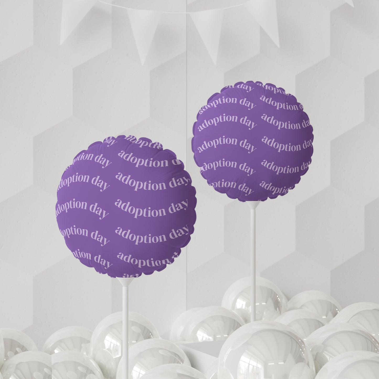 Purple 'adoption day' balloons on sticks with white balloons below against a geometric patterned background.